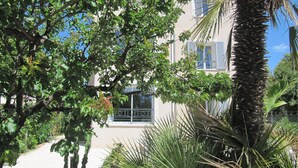Ein Gebäude mit Balkon, umgeben von üppiger Vegetation und einer Palme.