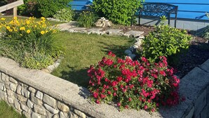 A blue house with yellow shutters, a stone wall, and a garden with flowers. - The Sister Bay Getaway: Water View & Downtown! Come enjoy Door County! (Sister Bay)