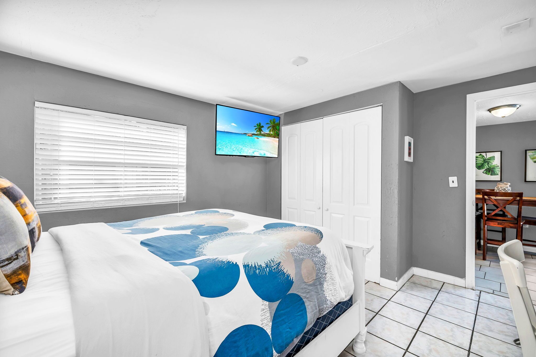 A bedroom with a bed, a TV, a closet, and a dining area.