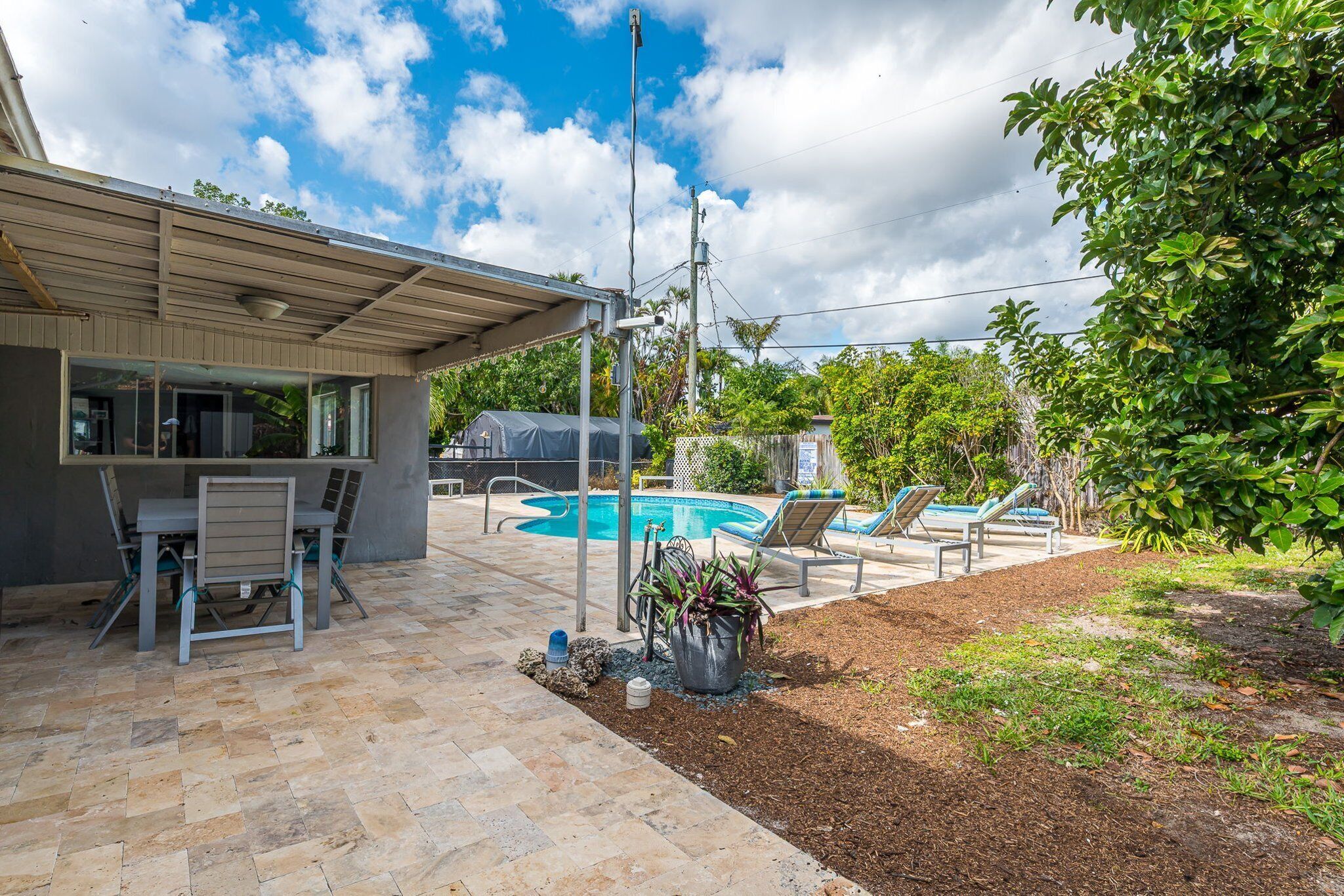 A backyard with a pool, outdoor seating, and a covered patio area.