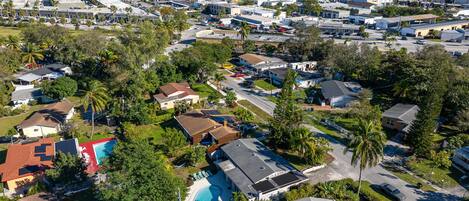 Vista aérea de un barrio residencial con casas, una piscina y cielo despejado.