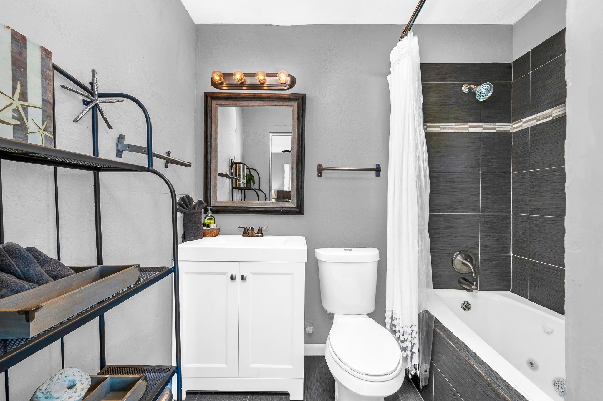 A bathroom with a white vanity, a toilet, a bathtub, and a shower.