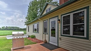 A house with a barbecue grill in the front yard, a door, and windows.