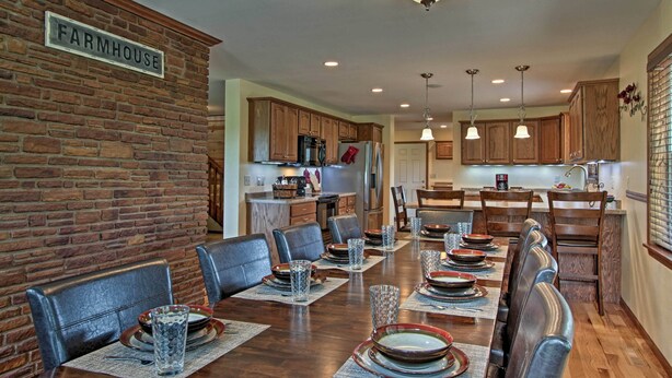 A dining area with a long wooden table set for a meal, surrounded by leather chairs.