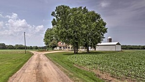 A rural landscape with a dirt road leading to a house with a barn.