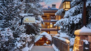 A snow-covered pathway leading to a hotel with a sign reading "Montaneros."