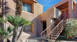 A building with a staircase, palm trees, and a door.