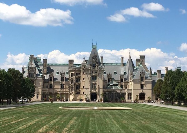 A large, historic building with a symmetrical facade, multiple chimneys, and a central entrance.