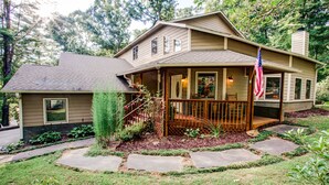 A two-story house with a covered porch, a flag, and a well-maintained garden.