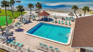 Un espace piscine avec vue sur l’océan, des chaises longues et un kiosque.
