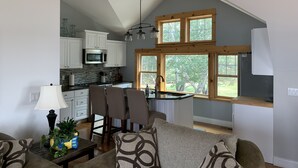 Una cocina moderna con armarios blancos, un microondas y un comedor con una mesa y sillas.
