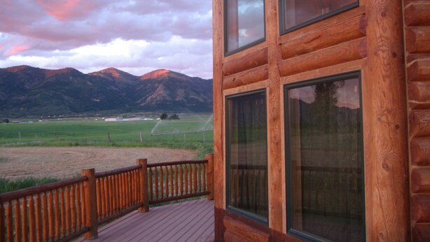 A wooden cabin with large windows overlooking a mountainous landscape. - Yellowstone, Grand Teton, Fish, Ski, Parks, Pets, Bike, Fire Pit, (Freedom)