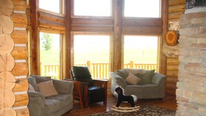 A log cabin interior with two sofas, a rocking horse, and a fireplace. - Yellowstone, Grand Teton, Fish, Ski, Parks, Pets, Bike, Fire Pit, (Freedom)