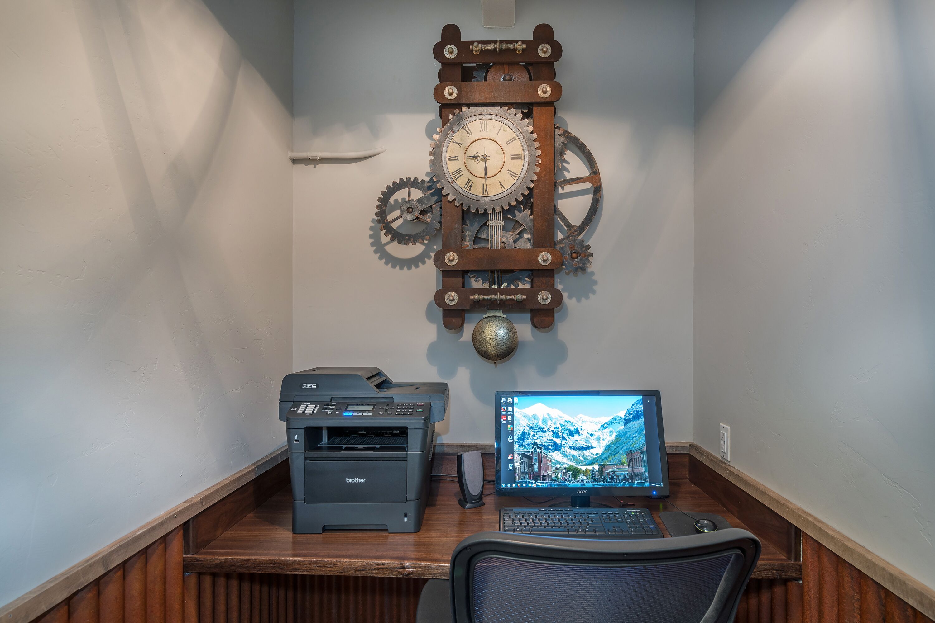 A wooden desk with a Brother printer, an Acer monitor, and a mechanical clock.