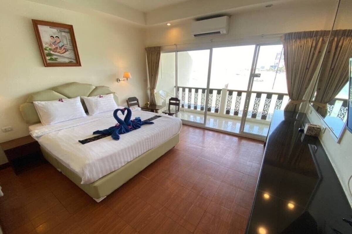 A hotel room with a bed, a TV, a balcony with a railing, and a window.