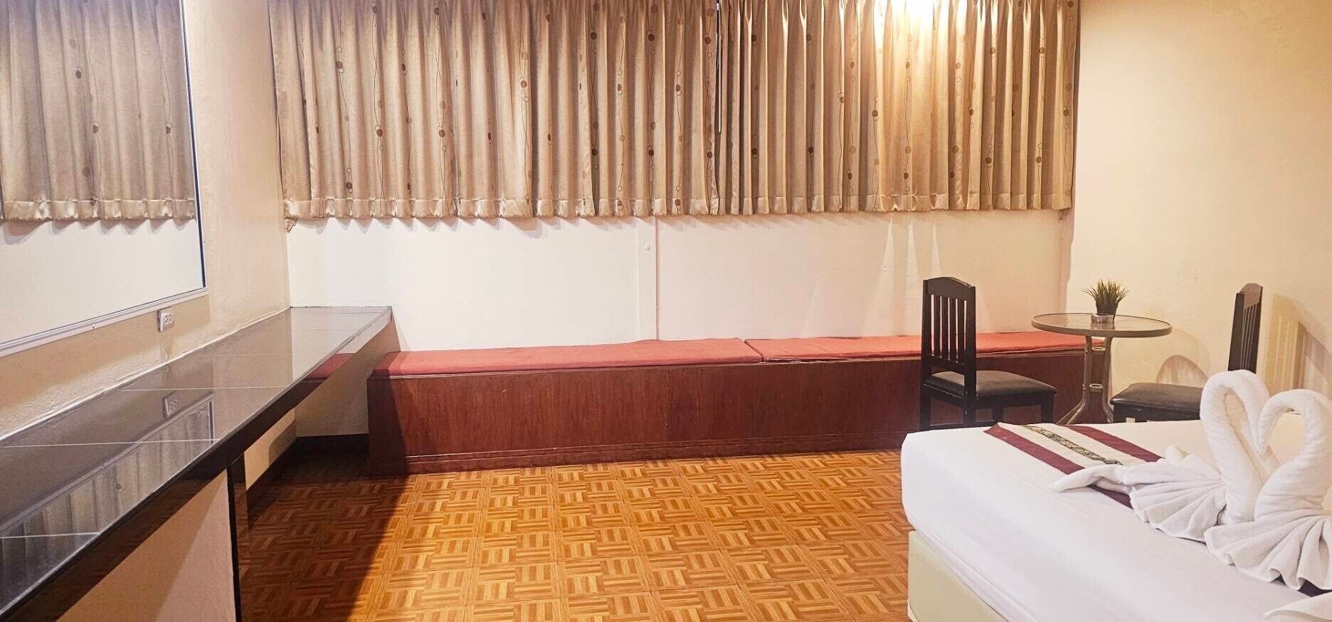 Une chambre d’hôtel avec un lit, une petite table, une chaise et un banc.