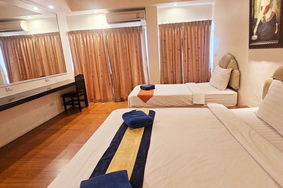 A hotel room with two beds, a desk, and a chair.