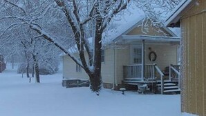 Una casa cubierta de nieve con un porche y escalones que conducen a la entrada.