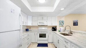 Cocina compacta con armarios blancos, microondas, estufa y lavabo.
