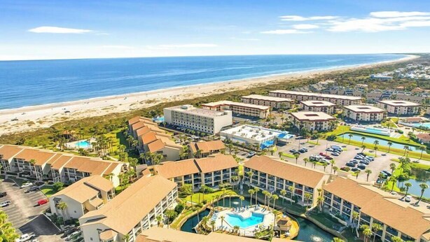 Un resort con varias edificaciones, una piscina y vista al mar.