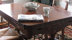Een houten eettafel met een mok met bloemen en een krant.