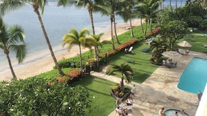 Een resort met zwembad, strand en palmbomen.