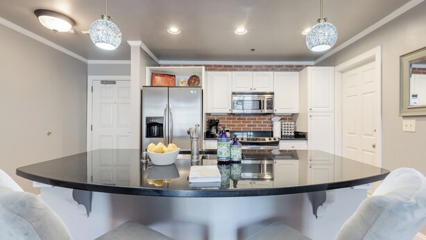 A kitchen with a central island, white cabinets, stainless steel appliances, and pendant lighting.