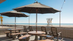 Espace extérieur aménagé avec des parasols, une tour de surveillance pour les sauveteurs et vue sur la plage.