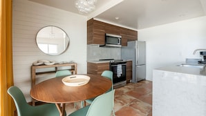 Une cuisine moderne avec une table de salle à manger ronde, des chaises vertes et un banc en bois.