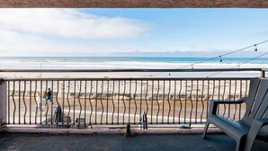 Un balcon donnant sur la plage, un banc et une rambarde.