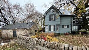 A stone wall with a sign reading "The Halfway Est. 1839" in front of a stone building and a blue house with a sloped roof.