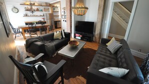 A living room with a sofa, chairs, a coffee table, a TV, and a staircase.
