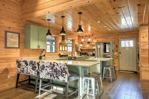 Interior de uma cabana rústica com cozinha, sala de jantar e banquetas.