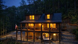 Eine zweigeschossige Holzhütte mit Balkon, Flagge und Kamin.