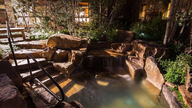 A stone water feature with a small waterfall, surrounded by rocks and greenery. - Luxurious Private Pet-Friendly River Club Residence (Telluride)