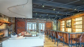 A spacious living area with a fireplace, a bar with stools, and a large sofa. - Luxurious Private Pet-Friendly River Club Residence (Telluride)