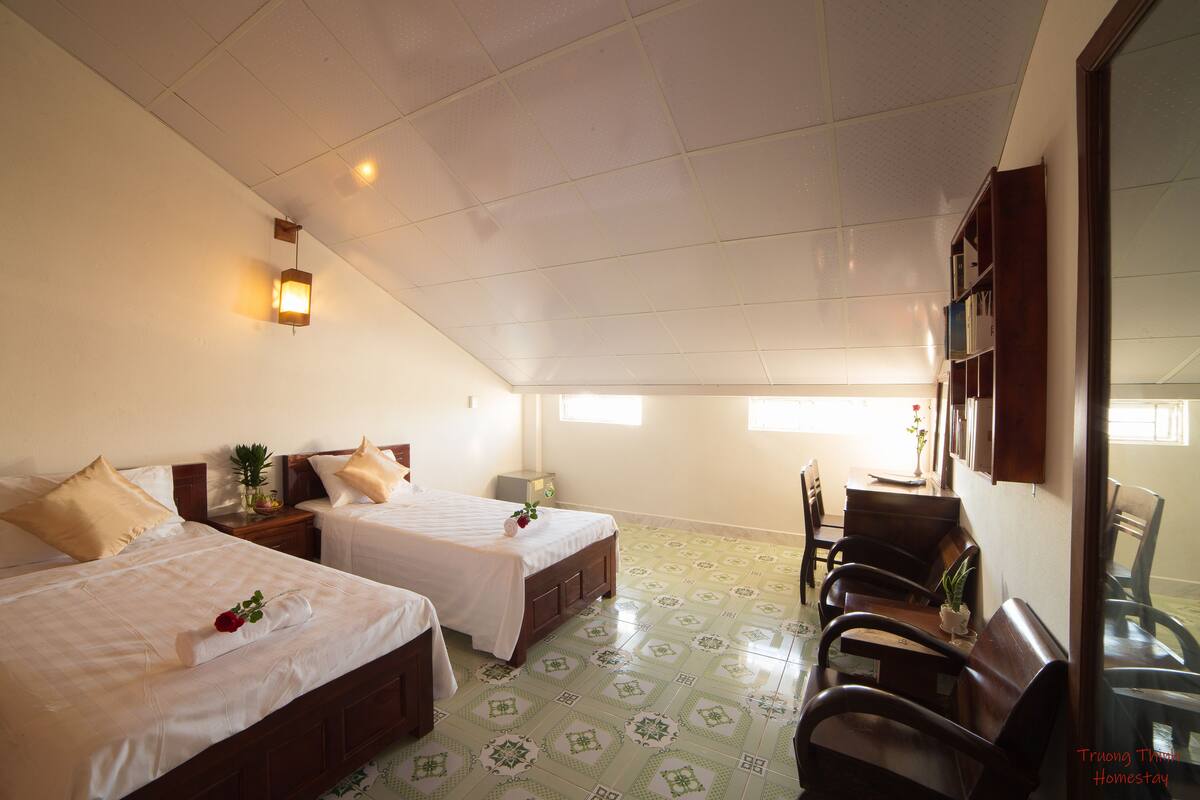 A hotel room with two beds, a dining table, and a seating area.