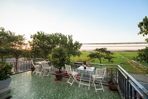 A terrace with a table and chairs, potted plants, and a view of a green landscape. - Truong Thinh Homestay (Da Nang)