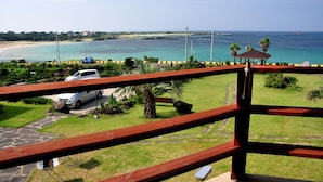 Une vue sur la côte depuis un balcon doté d’une balustrade en bois, avec une voiture garée et un kiosque.