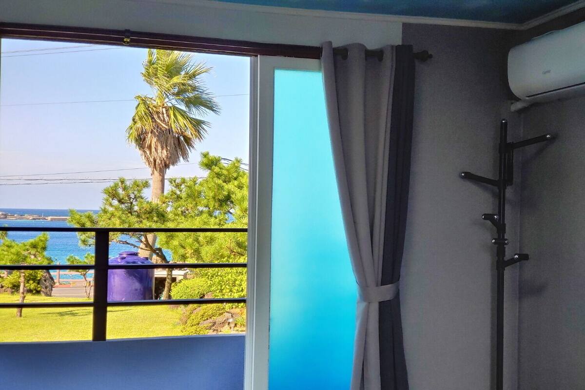 Ein Zimmer mit Meerblick, ein Balkon mit Geländer und eine Tür mit Vorhang.