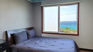 Une chambre à coucher avec un lit, une table de chevet et une fenêtre donnant sur la mer.