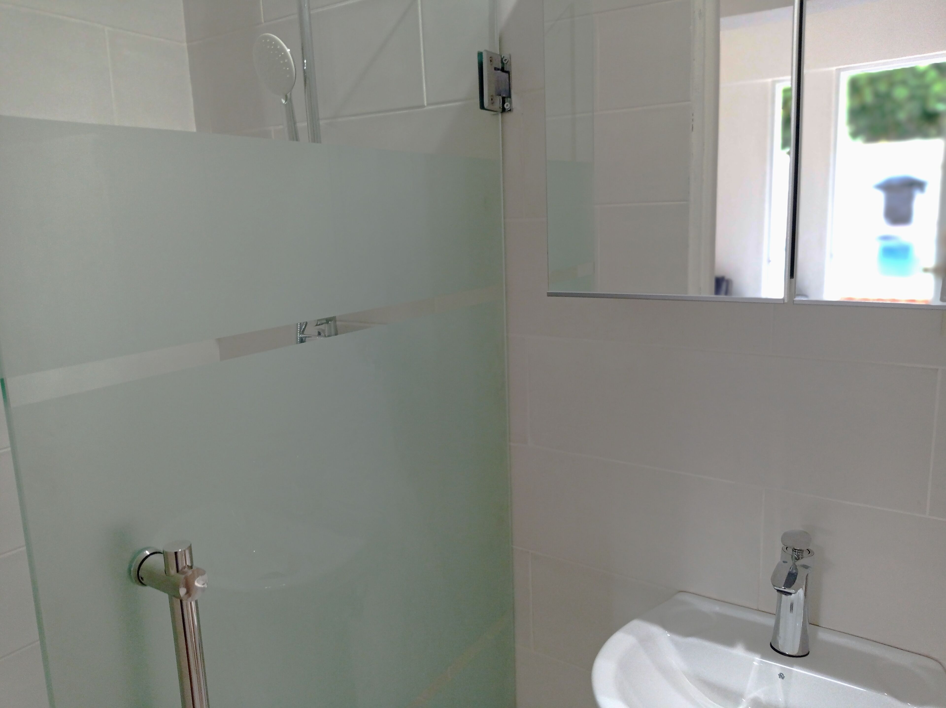 Un baño con cabina de ducha de vidrio, un lavabo y un espejo.