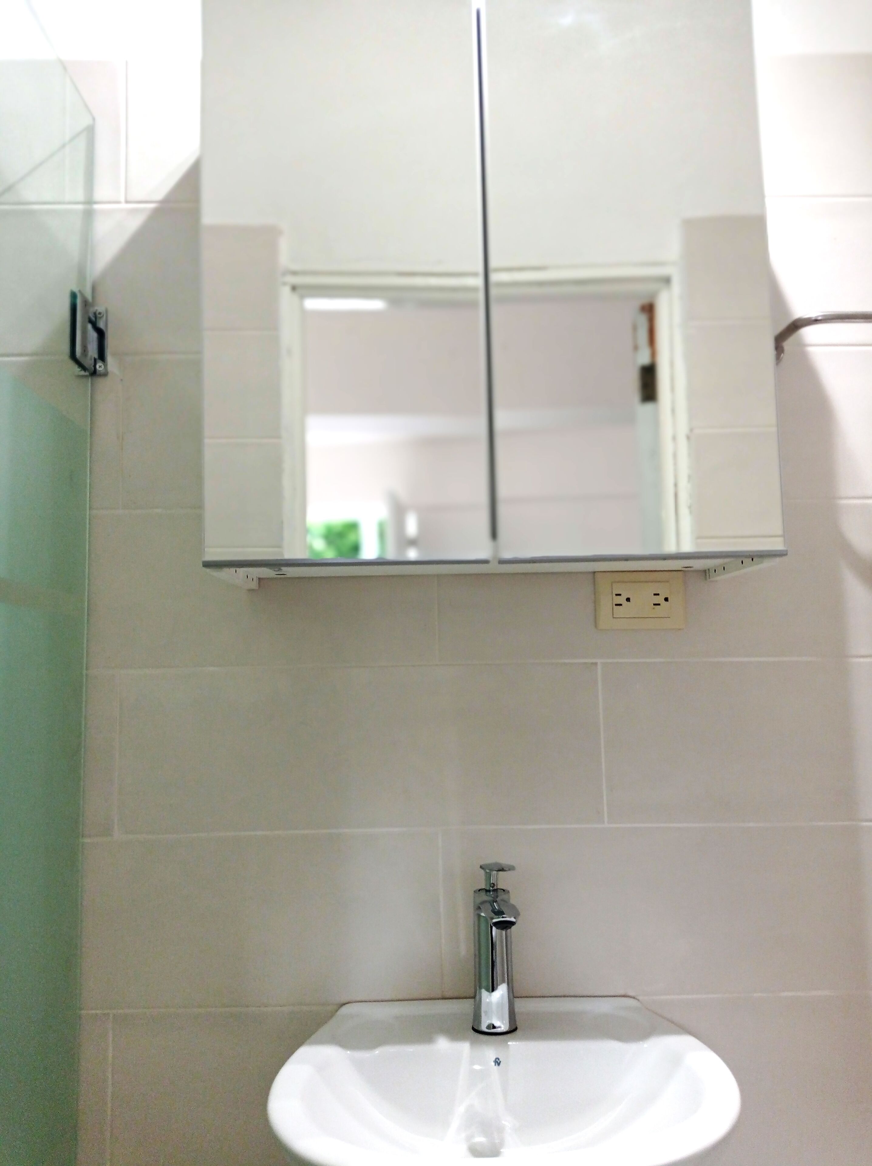 A bathroom with a white sink, a mirror above it, and a glass shower enclosure.
