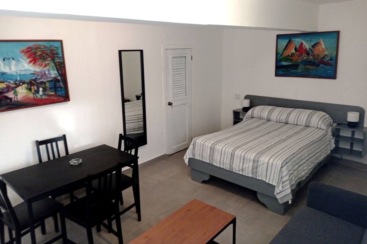 Une chambre à coucher comprenant un lit, un bureau, une chaise, un miroir et deux tableaux accrochés au mur.