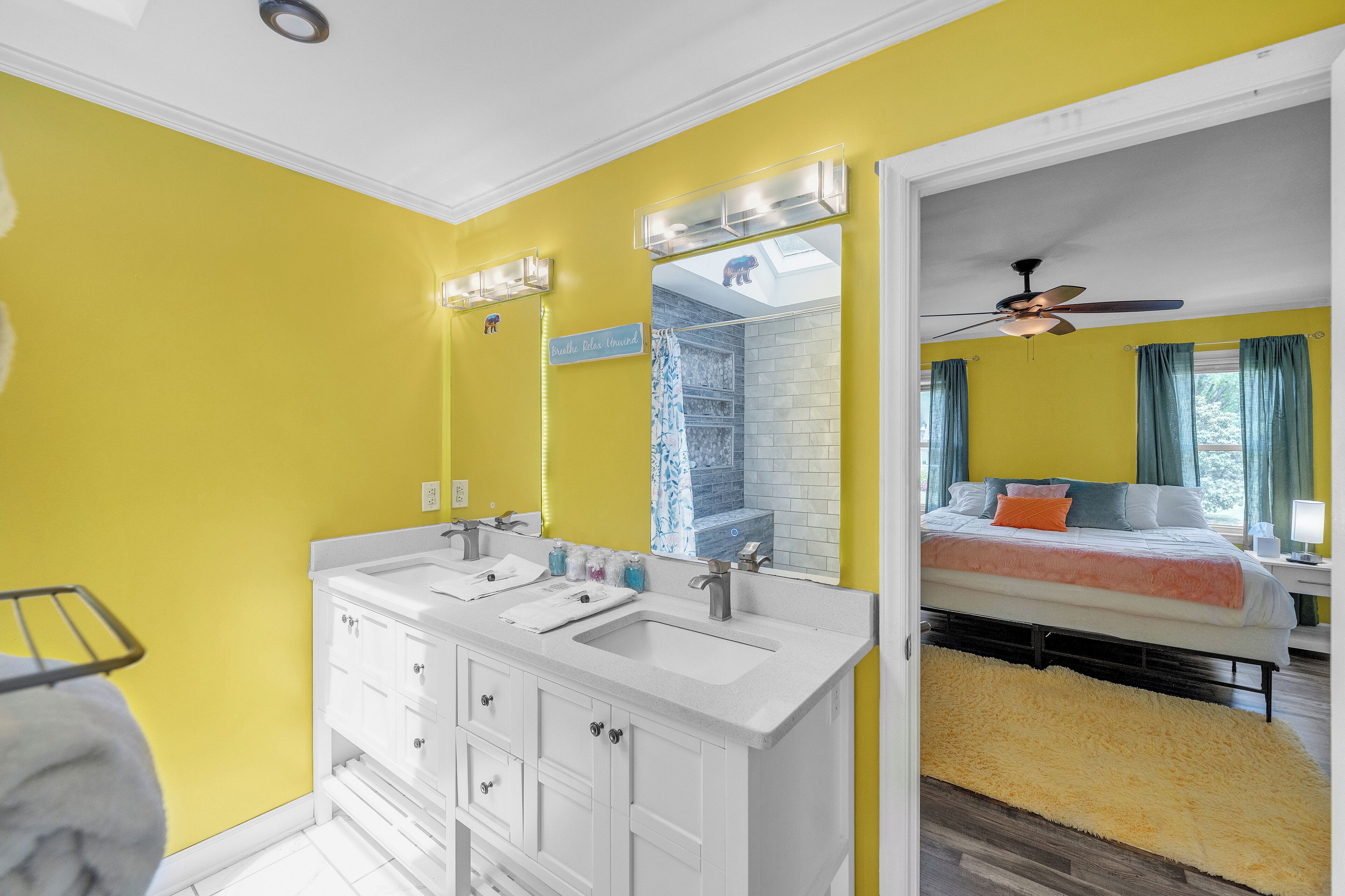 A bathroom with a double sink vanity, a mirror, and a ceiling fan.