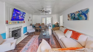 A spacious living room with a fireplace, a large TV, and a ceiling fan. - Kernersville Hot Tub  Pool  Arcade Gym Wifi Coffee (Kernersville)