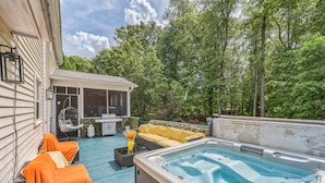 A covered outdoor deck with a hot tub, two lounge chairs with orange covers, a yellow sofa, and a small outdoor kitchen area. - Kernersville Hot Tub  Pool  Arcade Gym Wifi Coffee (Kernersville)
