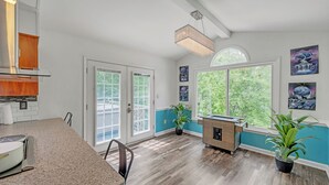 A spacious kitchen with a granite countertop, a wooden cabinet, and a built-in oven. There are two potted plants and a window with a view of greenery. - Kernersville Hot Tub  Pool  Arcade Gym Wifi Coffee (Kernersville)