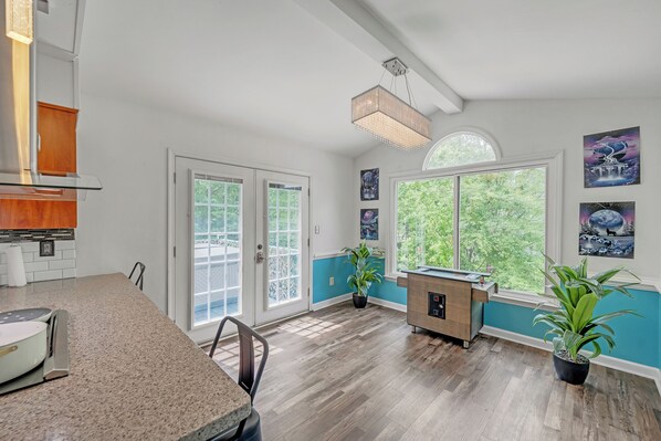 A spacious kitchen with a granite countertop, a wooden cabinet, and a built-in oven. There are two potted plants and a window with a view of greenery. - Kernersville Hot Tub  Pool  Arcade Gym Wifi Coffee (Kernersville)