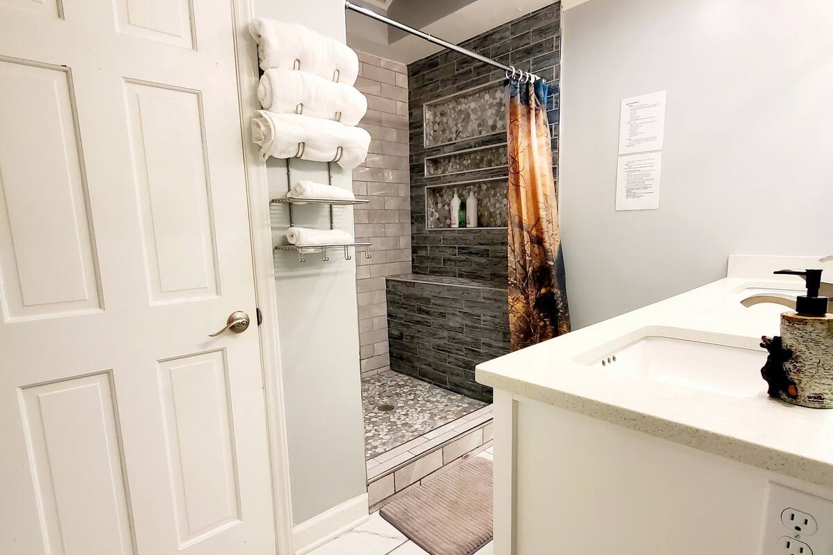 A modern bathroom with a shower, a white sink, and a towel rack.